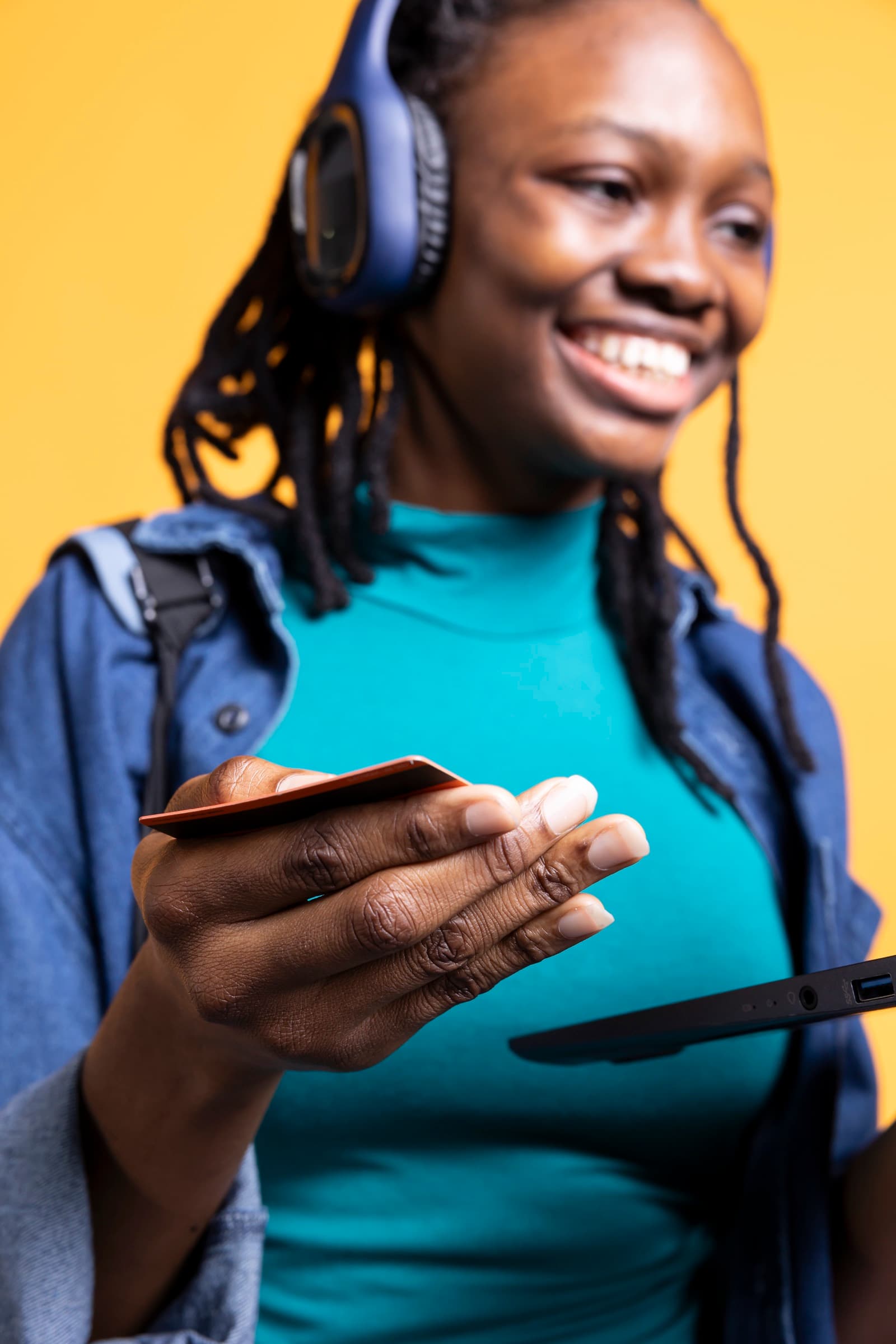 A smiling young woman holding up her bank card as she pays on a tablet